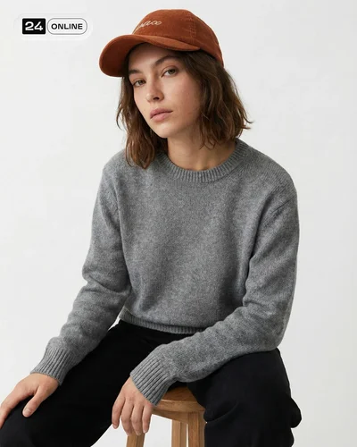 Minimal editorial studio photos of a casual embroidered cap on model and pedestal.